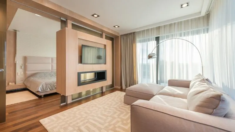 Suite con zona giorno: divano ad angolo, lampada ad arco e camino a parete, il letto sullo sfondo