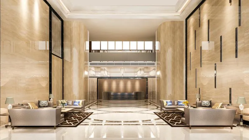 Hall d’albergo simmetrica: banco reception in fondo, due salotti affacciati e pareti in marmo chiaro a tutta altezza